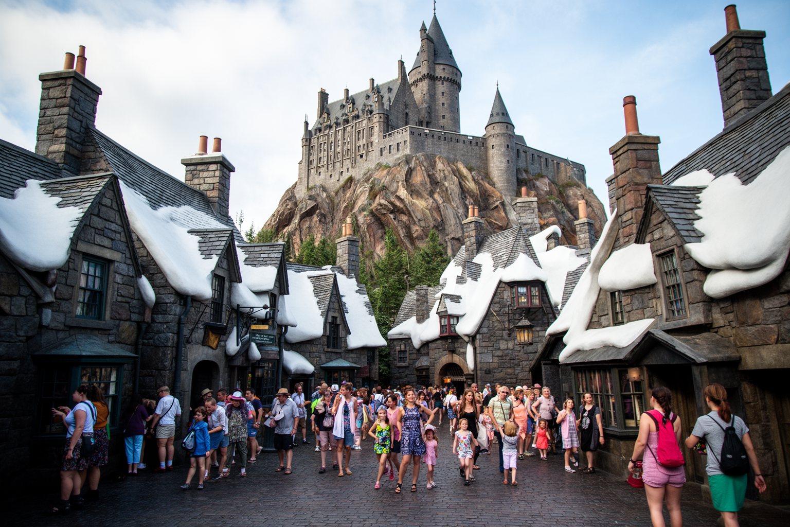 Snow-capped rooftops, cobblestones and a hilltop castle in Hogsmeade at Islands of Adventure