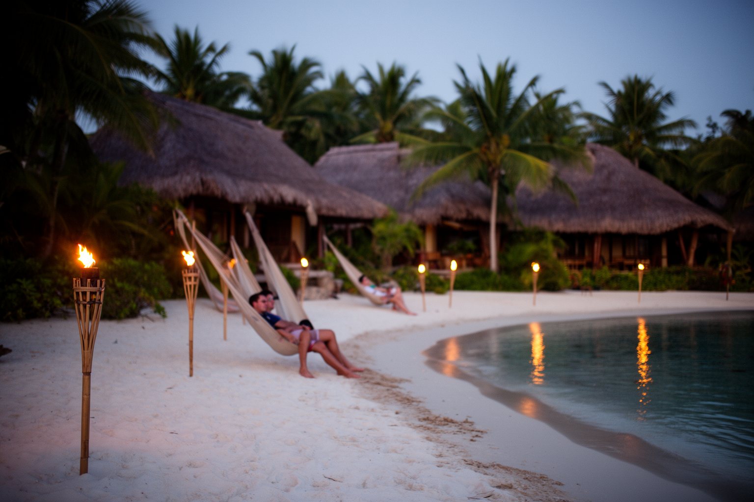 Tiki torches and hammocks on the beach at Disney's Polynesian Village Resort at dusk