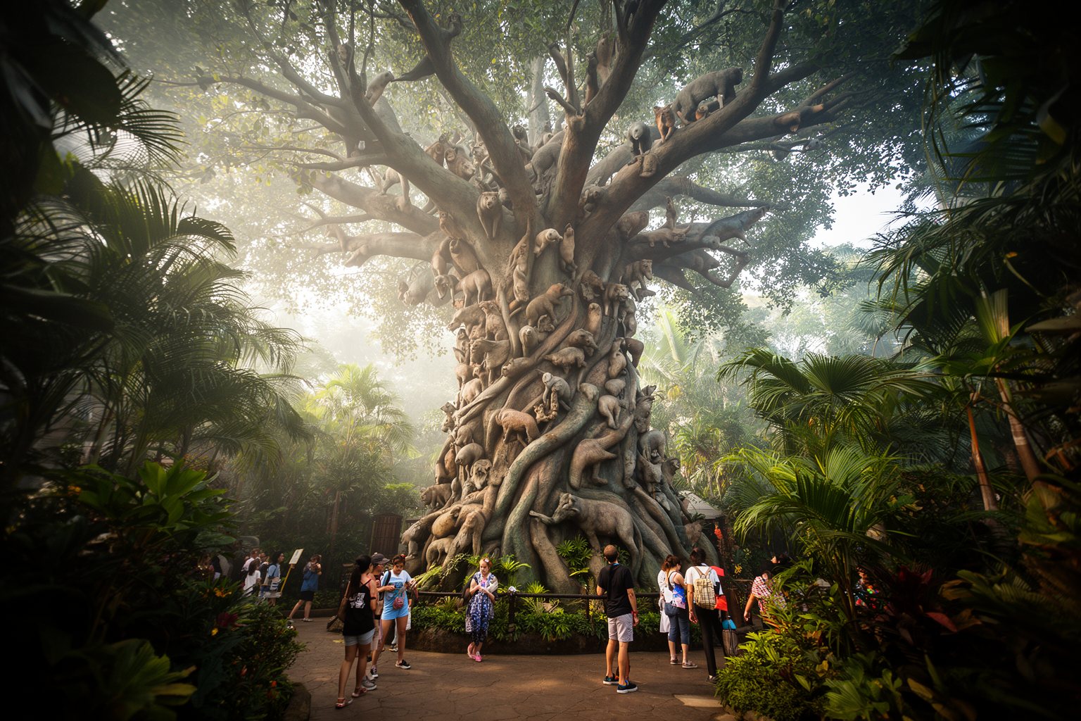 Visitors on a garden path beneath the carved Tree of Life at Animal Kingdom