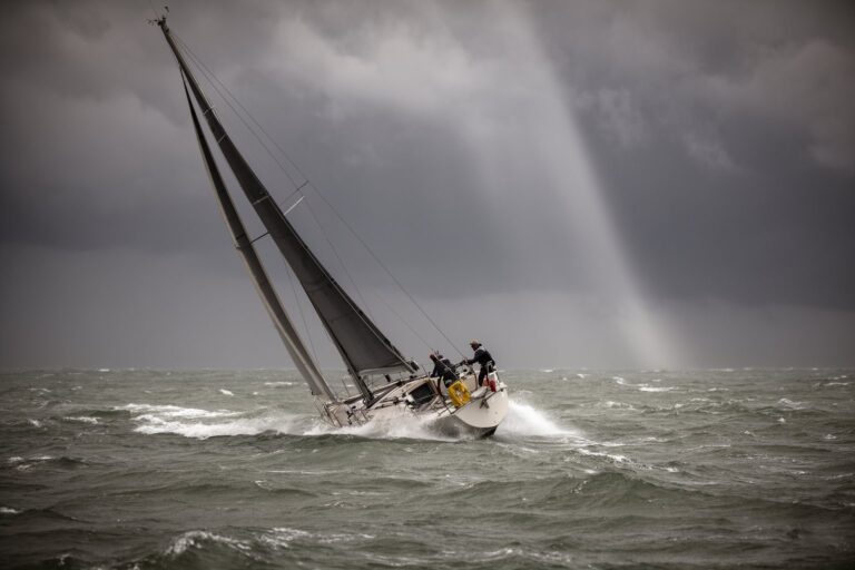 Sailboat heeling through rough waves under a dramatic sky, a metaphor for market volatility