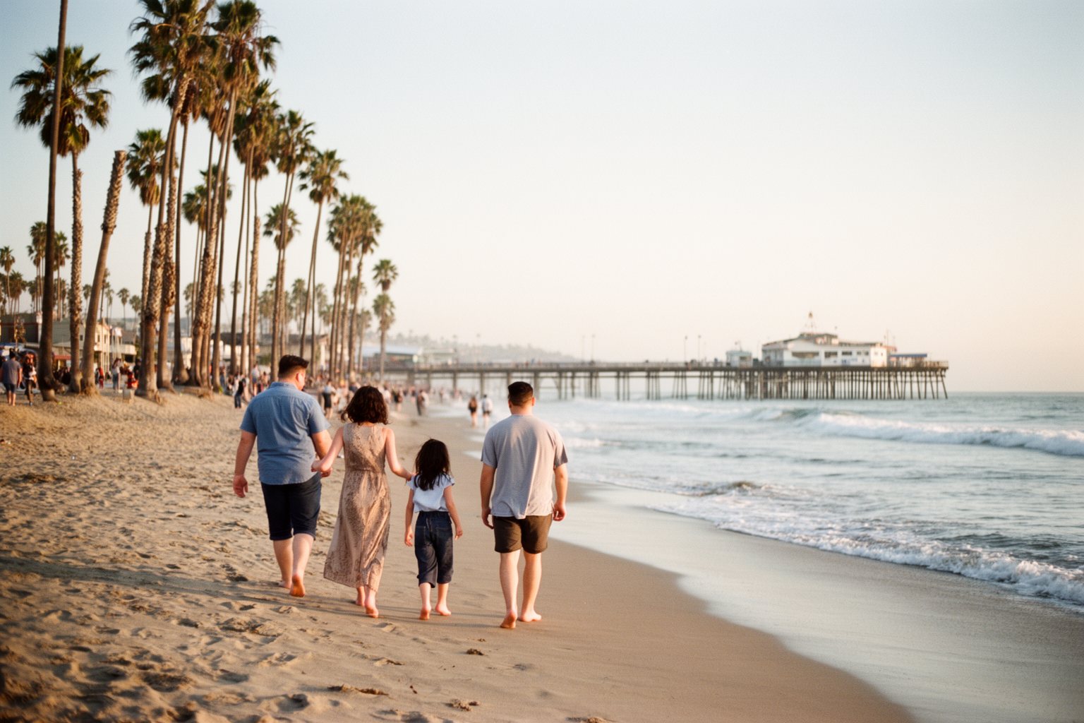 5 Best Family-Friendly Theme Parks Near Los Angeles Family walking on the sand at Santa Monica beach under tall palm trees in Los Angeles