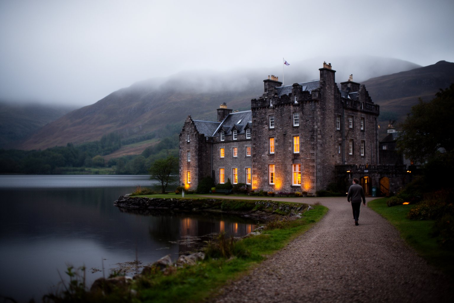 Historic castle hotel beside a Scottish loch at dusk with lit windows