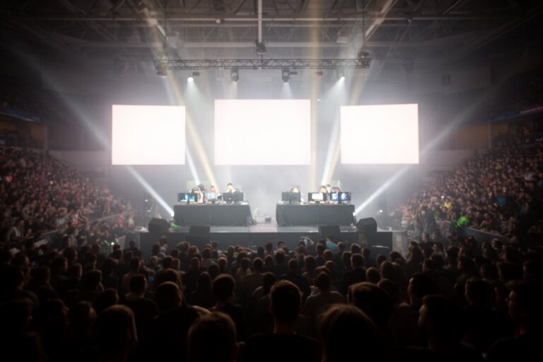 Esports and Social Networks: How Communities Drive Growth Packed arena crowd watching an esports final, players on a lit stage below giant screens