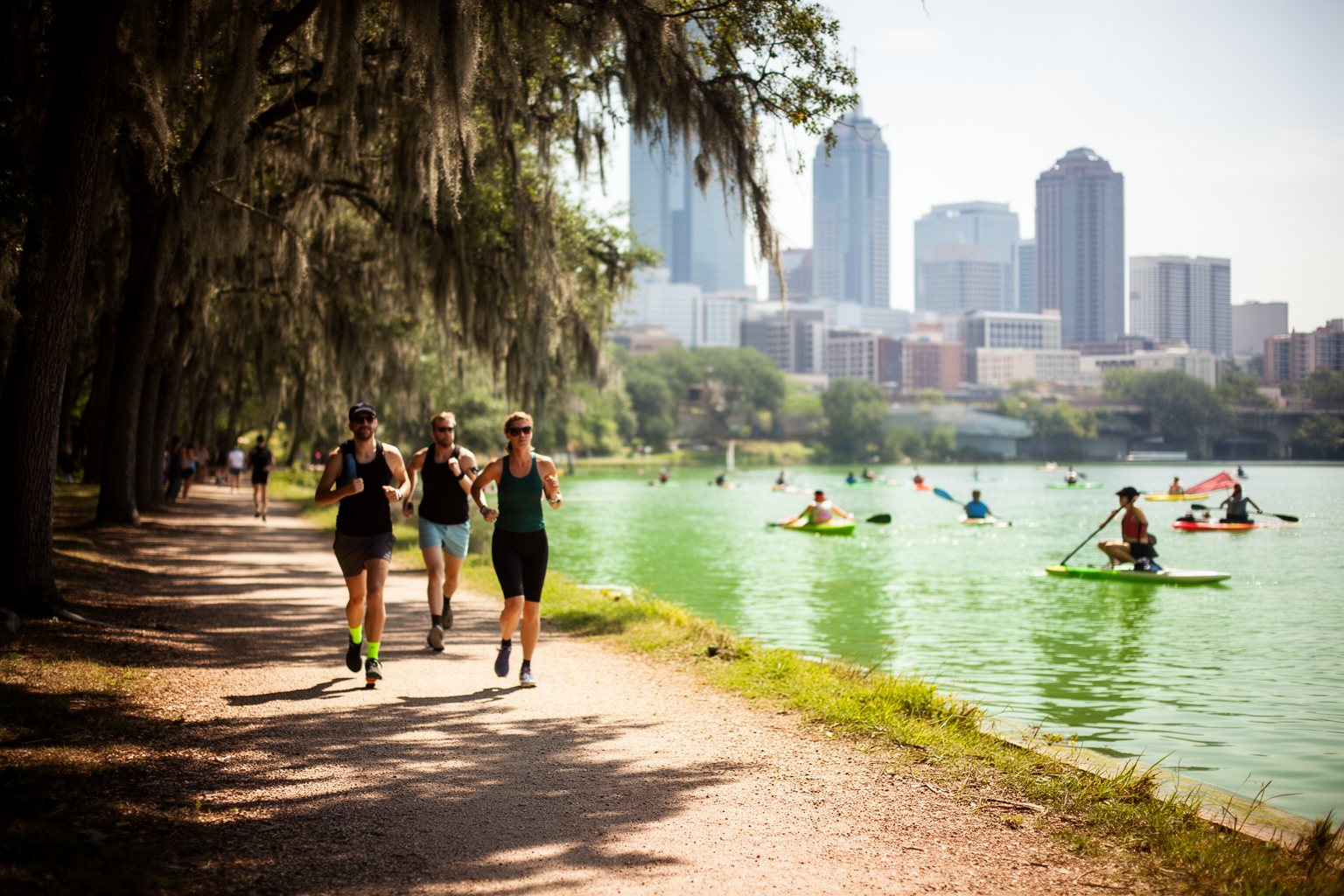 Jogging in Austin: Best Routes for Runners Joggers on the gravel Lady Bird Lake Trail beside kayakers, with the Austin skyline behind