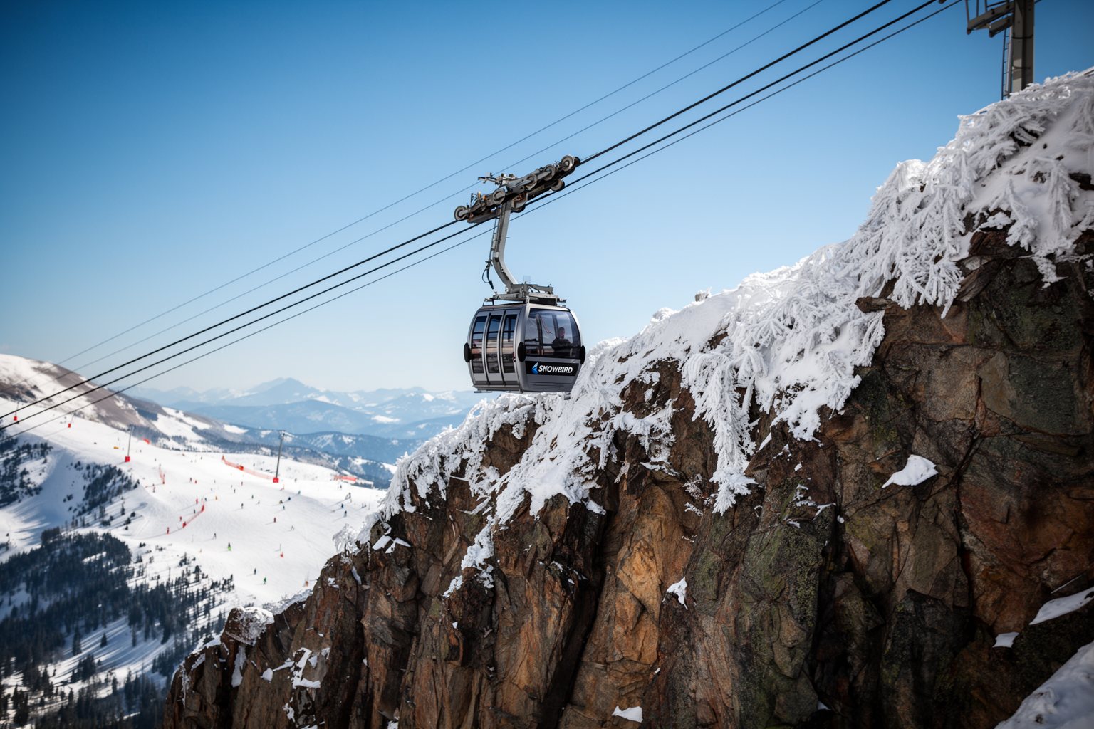 Utah Ski Towns: Park City, Alta, Snowbird and More Aerial tram cabin climbing above snowy cliffs at Snowbird in Little Cottonwood Canyon