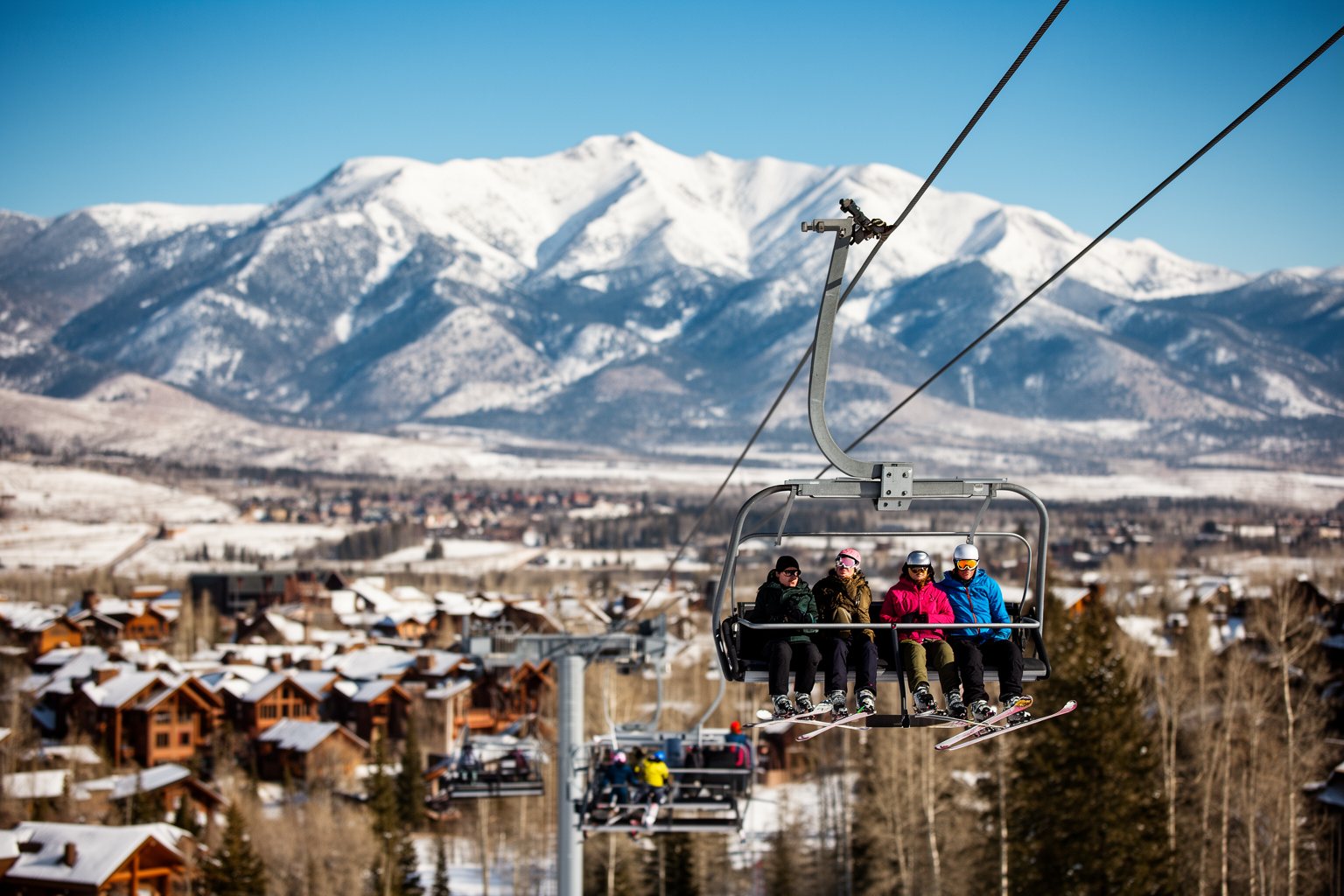 Utah Ski Towns: Park City, Alta, Snowbird and More Skiers above a Utah ski town on a bluebird morning, with snowy Wasatch peaks behind