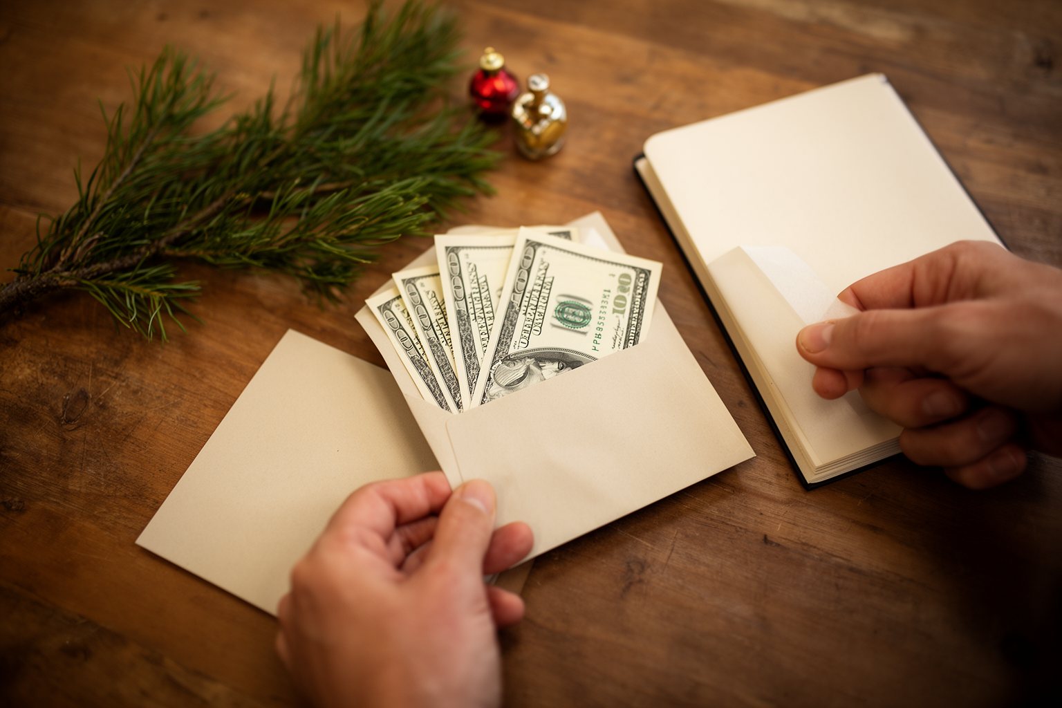 Hands dividing holiday cash into envelopes for gifts, food and decorations