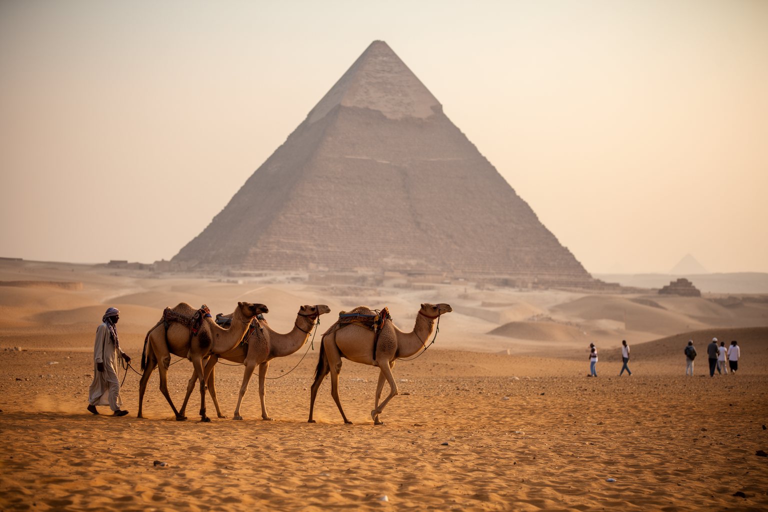 Unveiling the Top 10 Must-Visit Destinations: Your Ultimate Travel List Pyramids of Giza rising from the desert plateau near Cairo with camels and visitors in the foreground