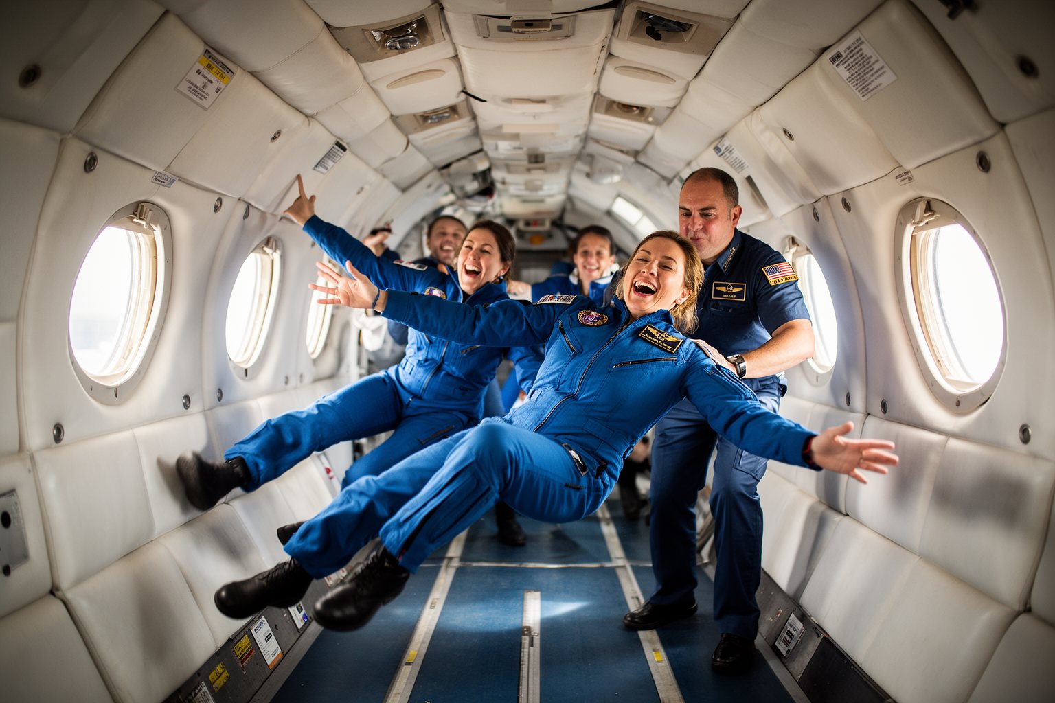 Adult passengers floating weightless and laughing inside a padded zero gravity aircraft cabin