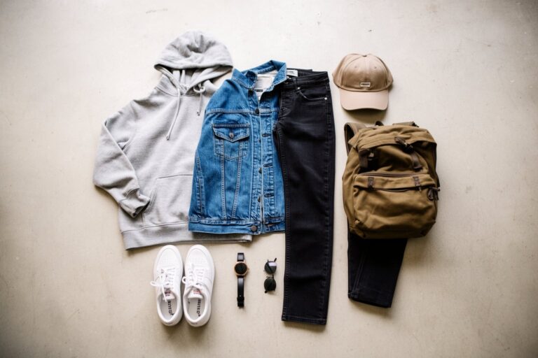 10 Must-Have Fashion Items for Teen Boys Flat lay of a hoodie, denim jacket, jeans, sneakers, cap and backpack, fashion items for teen boys