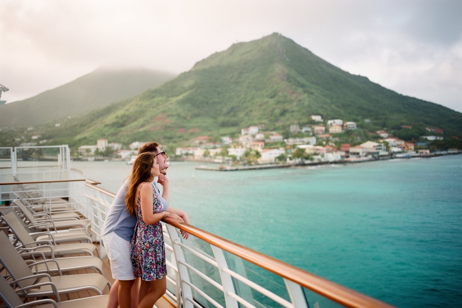 Couple on a cruise ship deck watching a Caribbean island approach, a cruise deal well booked