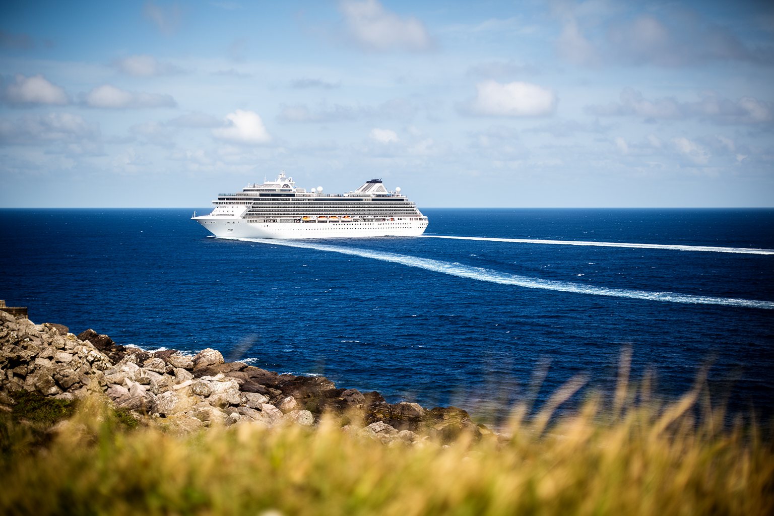 Large white cruise ship sailing across deep blue open sea