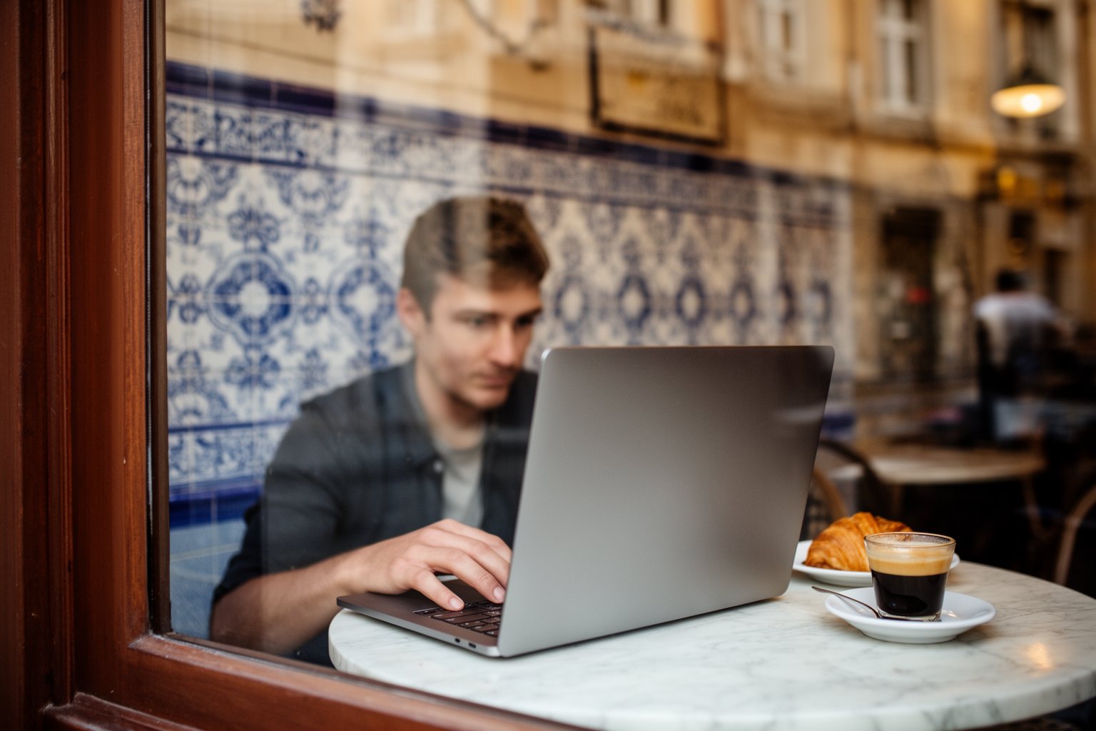 Unleash Your Freedom: The Ultimate Guide to Digital Nomadism Remote worker on a laptop in a tiled café in a European old town