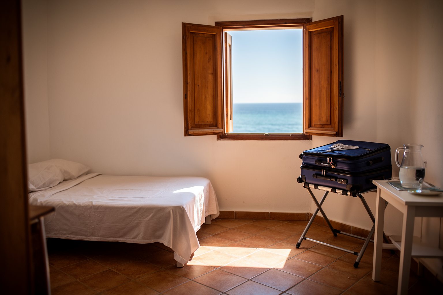 Cosy budget guesthouse room with open shutters and a sea view