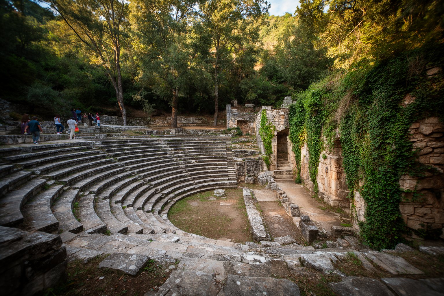 10 Unmissable Historical Sites in Europe You Didn't Know Existed! Stone seats of the ancient theatre at Butrint in Albania surrounded by trees and greenery