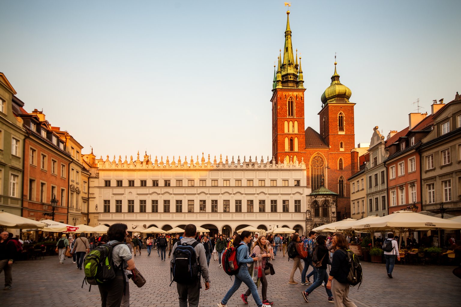 10 Budget-Friendly Backpacker Destinations to Explore Backpackers crossing Krakow's Main Market Square by the Cloth Hall and St Mary's Basilica towers