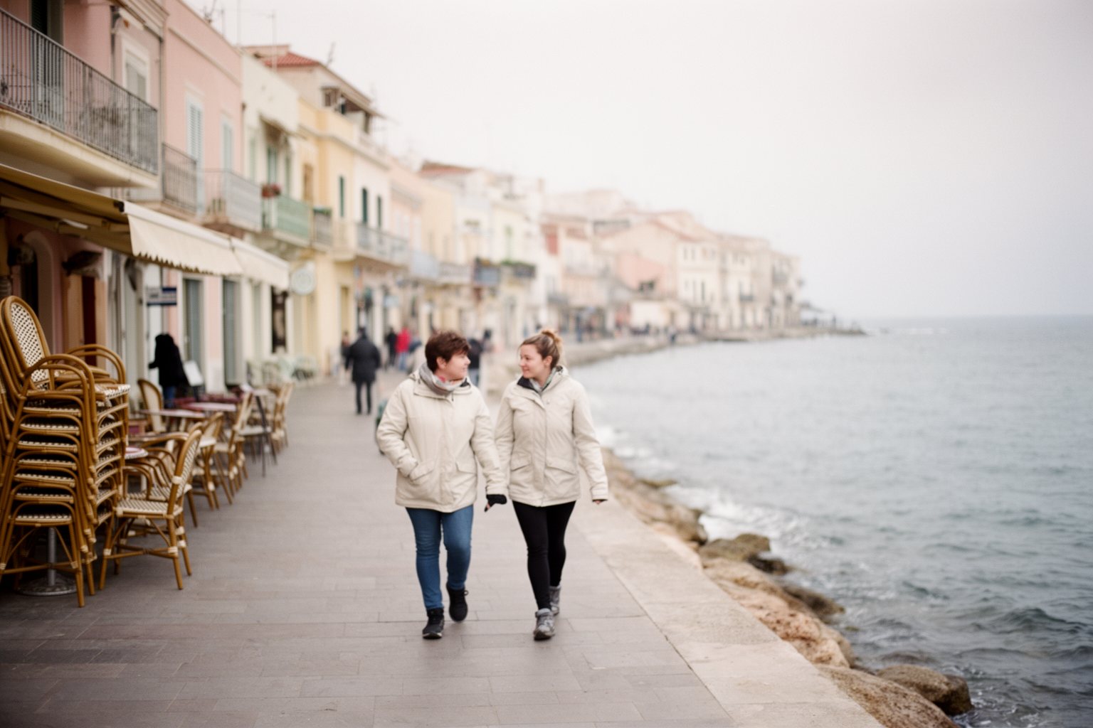 Couple walking a quiet Mediterranean seaside promenade in the off-season