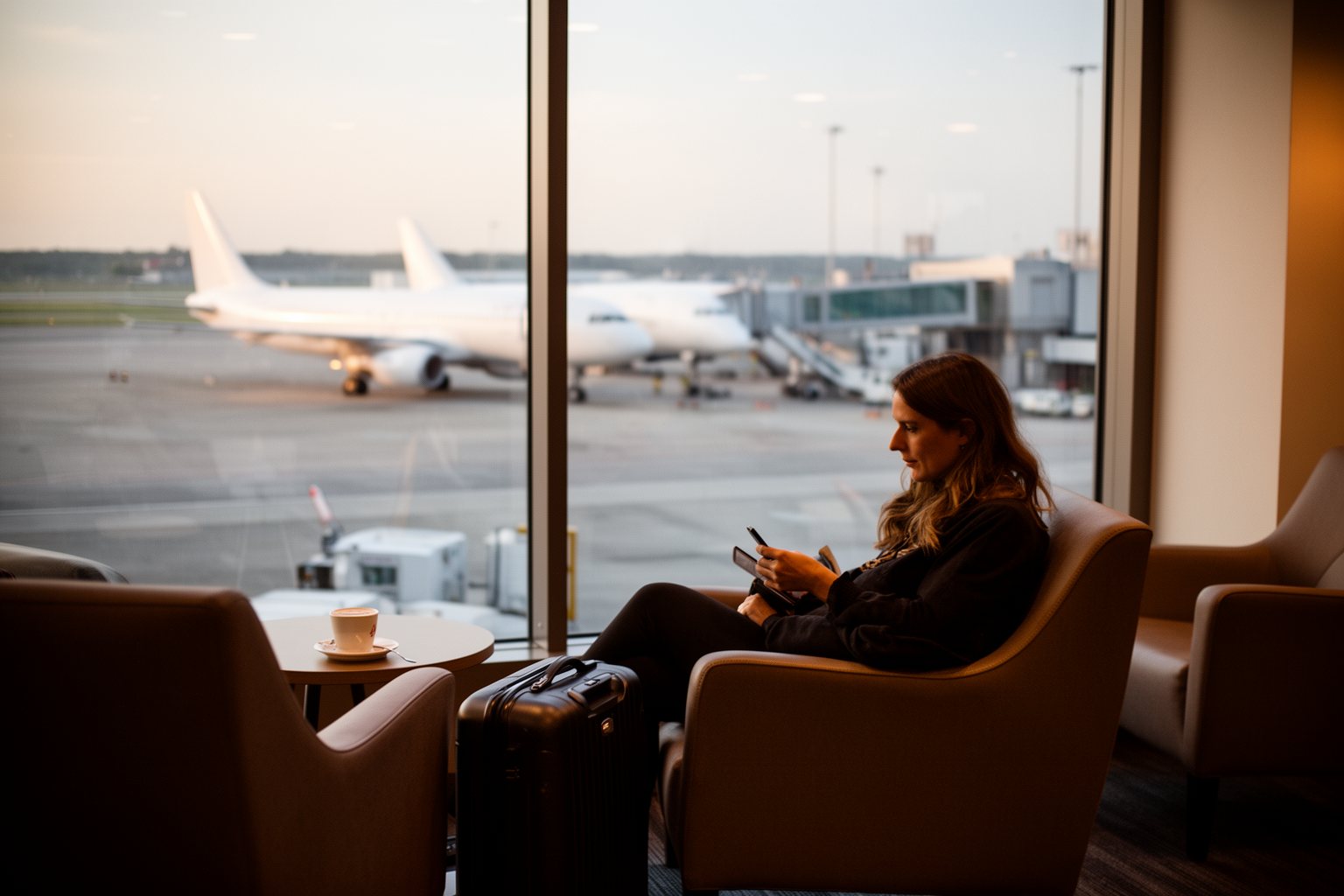 Traveller relaxing with coffee in an airport lounge by a window overlooking parked planes